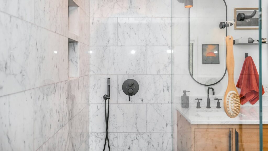 Ducha con rociador negro sobre azulejo blanco tras cambiar la bañera